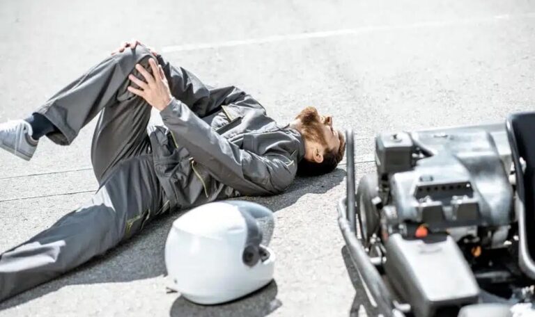 Motorcycle rider lying on road holding injured knee after auto accident representing knee injury claims in New York