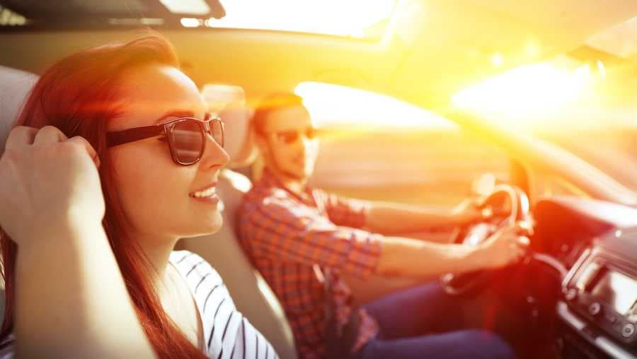 Couple driving car in summer sunshine representing safe driving tips for New York drivers