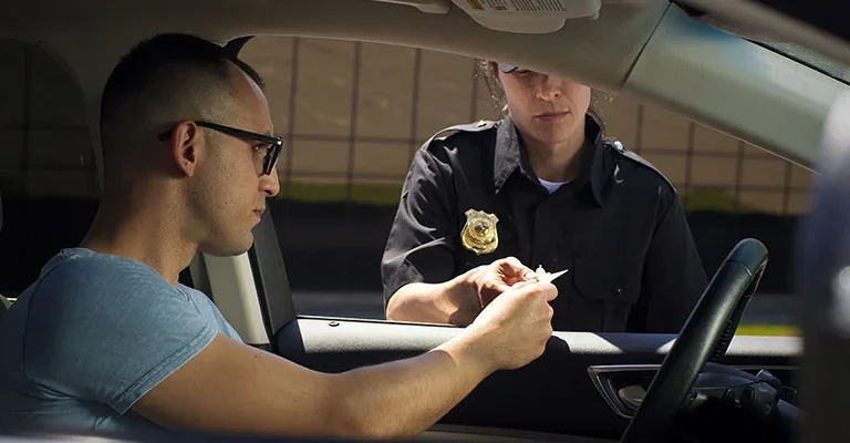 Driver handing license to police officer during a traffic stop