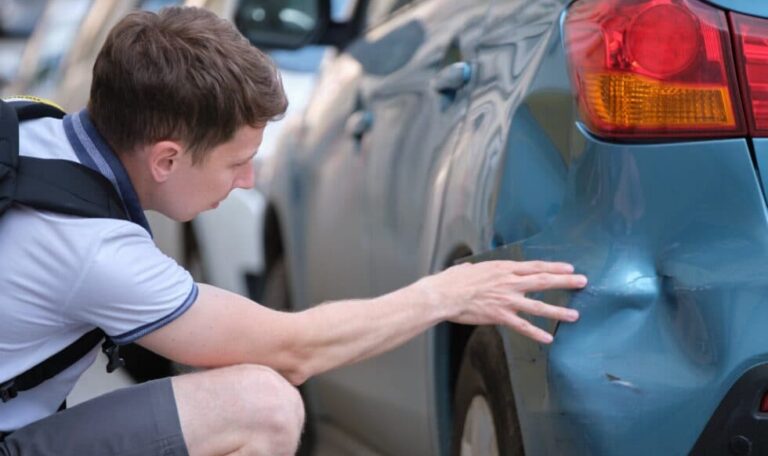 Man inspecting rear bumper damage after a rear-end collision in New York