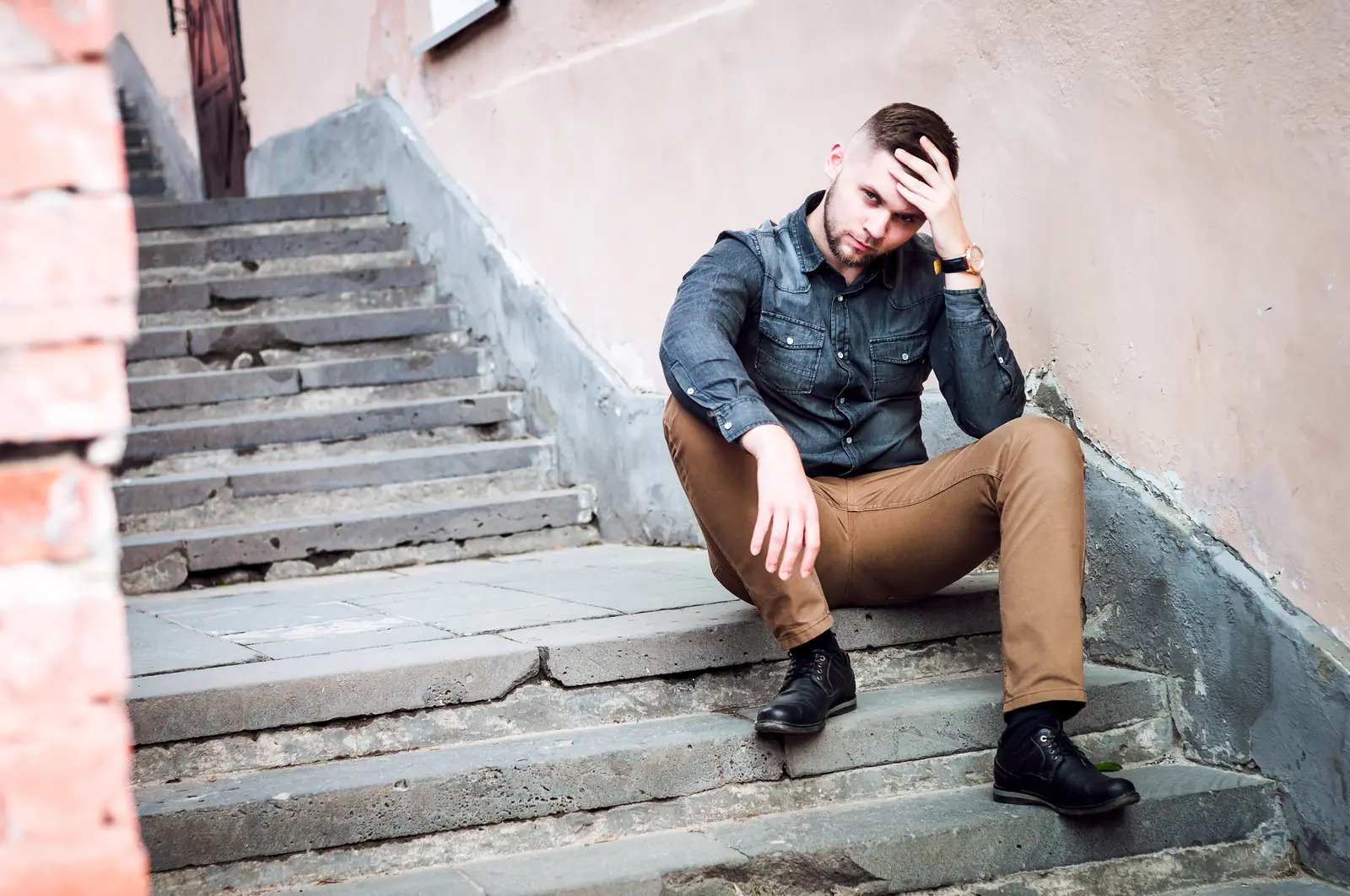 Injured man sitting on cracked, defective concrete stairs — defective staircase lawyer NYC