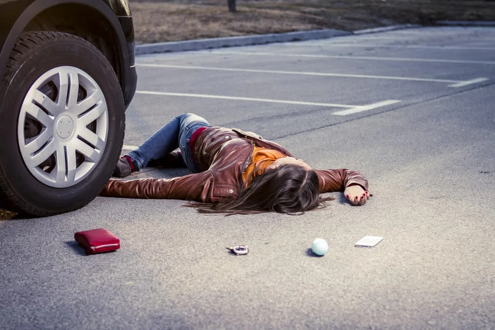 Pedestrian lying on the pavement after being struck by a vehicle, with belongings scattered nearby — pedestrian accident lawyer NYC