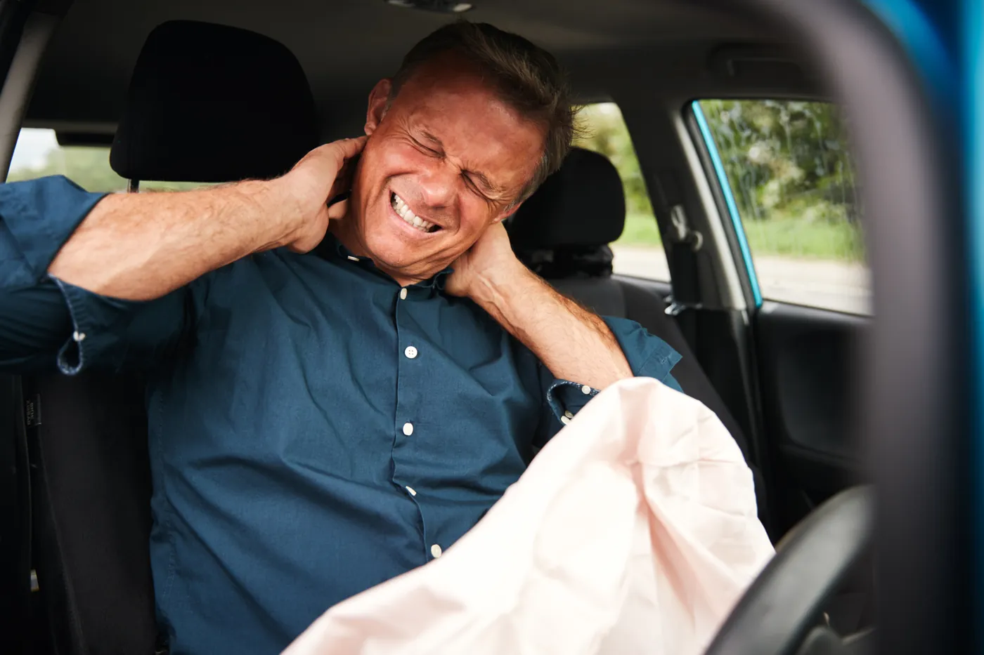 Driver holding his neck in pain after a car accident, a common cause of herniated disc injuries in Brooklyn
